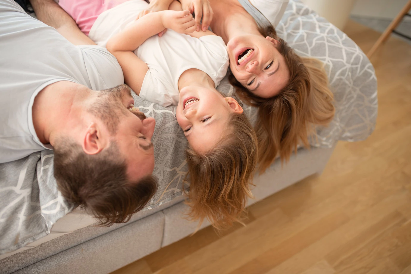 happy-young-caucasian-parents-laughing-while-lying-their-bed-with-their-little-daughter_181624-38501.webp